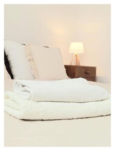 a white blanket on a bed next to a lamp at House Old Town Trogir in Trogir
