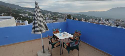 a table and chairs on a balcony with a blue wall at Casa Lotfi 1 in Chefchaouene