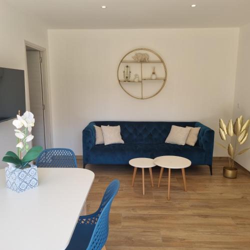 a living room with a blue couch and two tables at Rez de villa avec piscine, wifi, jardin clôturé in Penta-di-Casinca