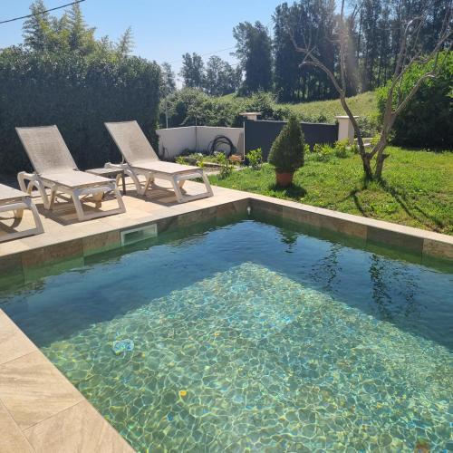 a swimming pool with two chairs and a pool of water at Rez de villa avec piscine, wifi, jardin clôturé in Penta-di-Casinca