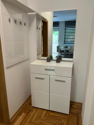 cocina con armarios blancos y espejo en Centar NS, en Novi Sad