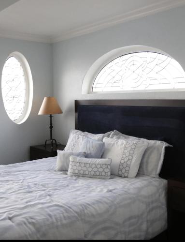 a bedroom with a white bed with two windows at Hotel Breakers in Gualala