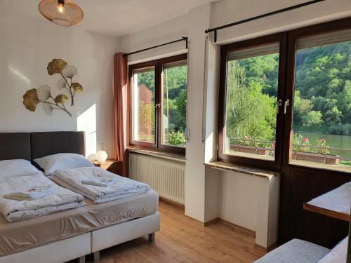 1 dormitorio con 2 camas y 2 ventanas en Römerstube Apartments & rooms, en Ediger-Eller