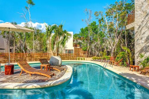 - une piscine avec 2 chaises et un parasol dans l'établissement Nature Luxury Selva Norte, à Tulum