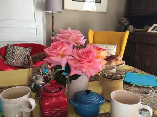 a table with a vase with pink flowers on it at Chambres d Hôtes Les Filles Tresy in Passenans