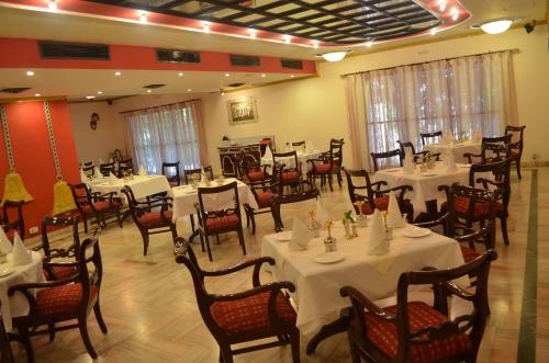 a dining room with white tables and chairs at The Radha Ashok in Mathura
