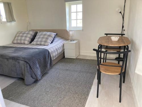 ein Schlafzimmer mit einem Bett, einem Tisch und einem Stuhl in der Unterkunft Tiny house du Haras Cour Lozey in Sainte-Marguerite-des-Loges