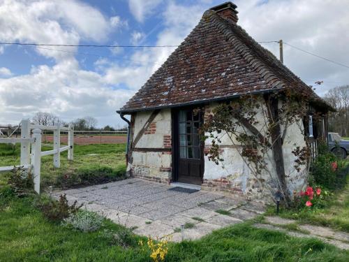 una vieja cabaña en un campo con una valla blanca en Tiny house du Haras Cour Lozey, en Sainte-Marguerite-des-Loges