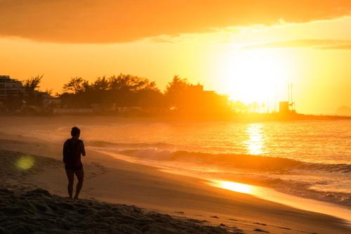 a man standing on the beach watching the sunset at Longboard Paradise Surf Club in Rio de Janeiro