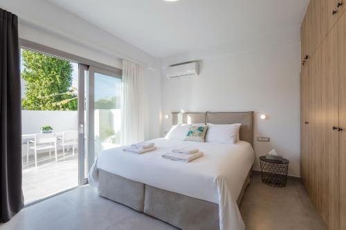 a white bedroom with a large bed and a balcony at Hermes&Dione in Argoulidhés