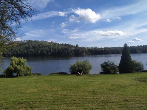 einen Blick auf einen See mit zwei auf dem Rasen sitzenden Personen in der Unterkunft Apartmán 10 in Županovice