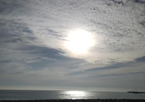 a sun in a cloudy sky over the ocean at Bird House in Lourinhã