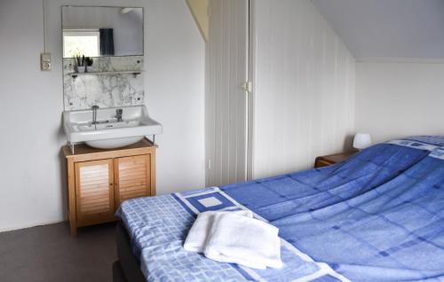 een slaapkamer met een blauw bed en een wastafel bij De Duun in Nes