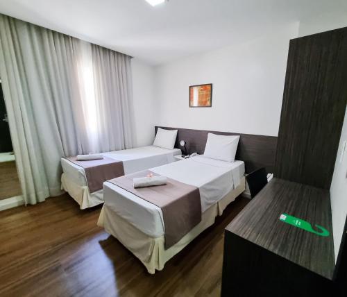 two beds in a hotel room with a green thermometer at Trópico Praia Hotel in Maceió