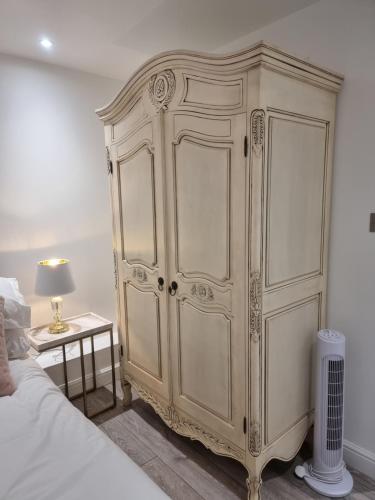 a large white cabinet in a bedroom next to a bed at 3 Minute Walk to Beach - Couldn't be much closer to sea in Bournemouth