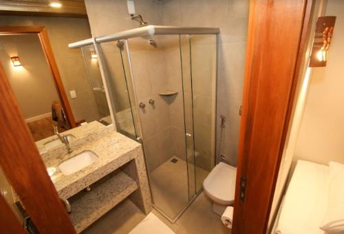 a bathroom with a shower with a sink and a toilet at Suítes Novas no Coração de Bonito in Bonito