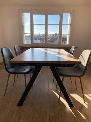 een eettafel met 4 stoelen en een raam bij Superbe appartement proche CV in Bourges