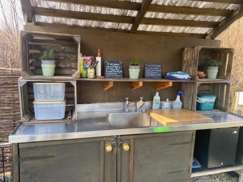 an outdoor kitchen with a sink and shelves at Belan Bluebell Woods Shepherds Hut in Llanidloes