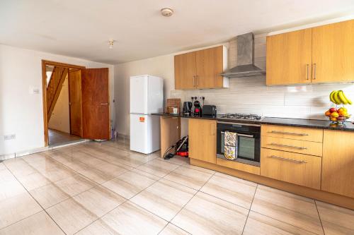 a kitchen with wooden cabinets and a white refrigerator at Beautiful 4 bedrooms house, 7 walk to train station in Plumstead
