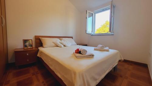 een slaapkamer met een bed met handdoeken en een raam bij Silba Belvedere (2) 45m from the beach in Silba