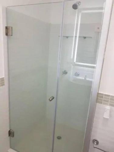 a white bathroom with a shower and a toilet at Ecusuites Jacuzzi en Playas Vista Mar in Playas