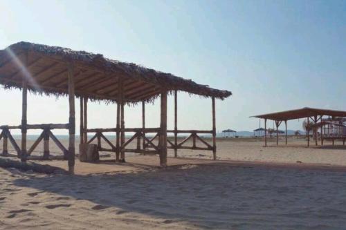 a group of wooden shelters on a beach at Ecusuites Jacuzzi en Playas Vista Mar in Playas