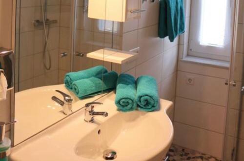 a bathroom with a sink with green towels on it at Haus-Elbromantik-Sandau in Sandau