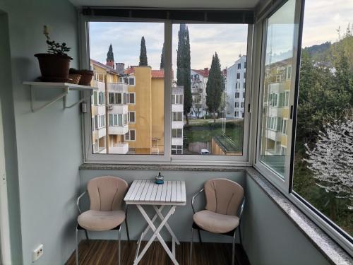 ein kleiner Tisch und zwei Stühle in einem Zimmer mit zwei Fenstern in der Unterkunft Apartment T&T in Lovran