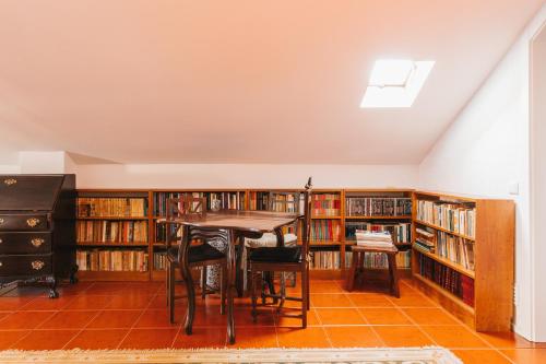 a library with a table and some book shelves at Bird House in Lourinhã