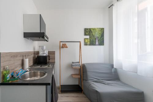 une petite salle de bain avec un lavabo et un lit dans l'établissement Le Tinchon, à Valenciennes