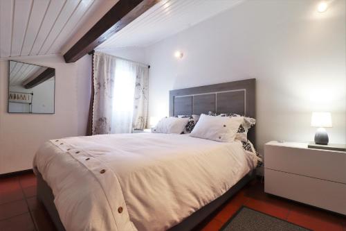 een slaapkamer met een groot wit bed en een raam bij Casa Quinta das Férias in Ginetes