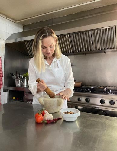 a woman in a kitchen preparing food in a bowl at Masia Sagués in Poblet