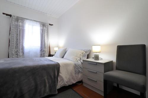 a bedroom with a bed and a chair and a window at Casa Quinta das Férias in Ginetes