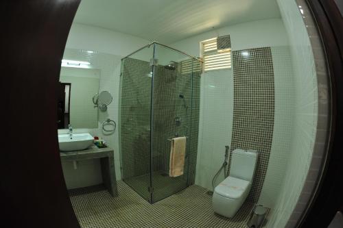 
a bathroom with a toilet, sink, and shower stall at Anantamaa Hotel in Trincomalee
