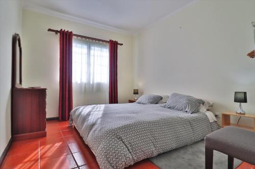 a bedroom with a bed and a window with red curtains at Casa Quinta das Férias in Ginetes