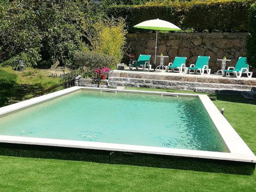 a large swimming pool with chairs and an umbrella at Casa do Casal in Guimarães