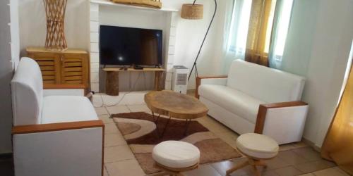 a living room with white furniture and a tv at Appartement haut standing avec piscine in Yaoundé