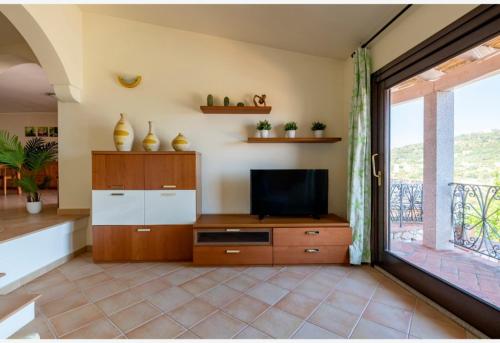 a living room with a television and a balcony at porto frailis Arbatax casa vista mare in Àrbatax