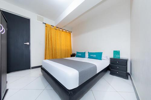 1 dormitorio con 1 cama grande y cortina amarilla en Ayenda Vittapark, en Medellín