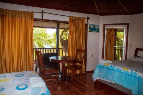 a bedroom with two beds and a table and a window at Coconut Tree West Bay in West Bay