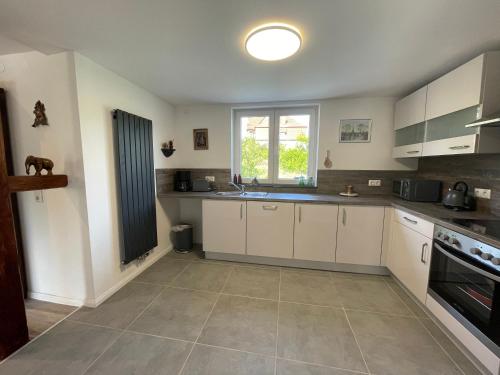 a kitchen with white cabinets and a window at Maharaja Ferienhaus in Hemfurth-Edersee