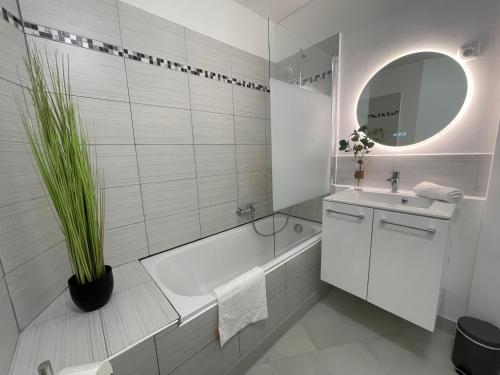 une salle de bain avec une baignoire blanche, un lavabo et un miroir dans l'établissement La Parenthèse, Disneyland & Shopping, à Serris