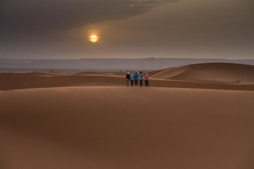 Trzy osoby stojące na wydmie piaskowej na pustyni w obiekcie I Sahara Camp w mieście Merzouga