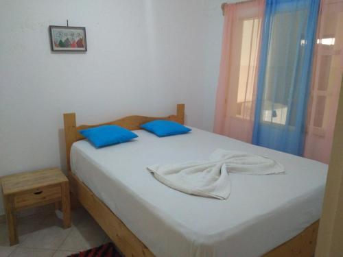 聖菲利佩的住宿－Pensão Domingas，一间卧室配有一张带蓝色枕头的床和一扇窗户。