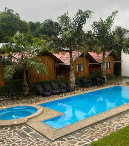 a pool in front of a resort with palm trees at La Posada de Mindo in Mindo