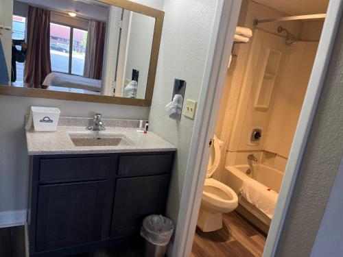 a bathroom with a sink and a toilet and a mirror at Days Inn & Suites by Wyndham Dayton North in Dayton