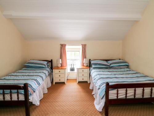 two twin beds in a room with a window at Grange Farmhouse in Fethard on Sea
