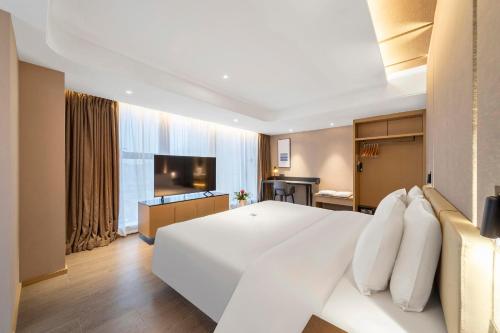 1 dormitorio con 1 cama blanca grande y TV en Atour Hotel Ya an Era Street, en Ya'an