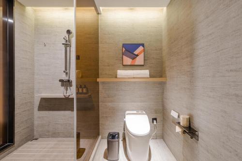 a bathroom with a shower and a toilet and a sink at Atour Hotel Jiaxing Pinghu in Pinghu