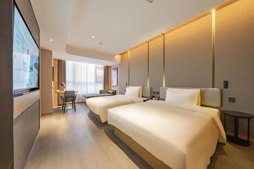 a hotel room with three beds and a television at Atour Hotel Huai an Suning Plaza Dazhi Road in Huai'an